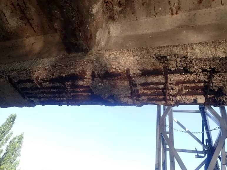Poutre en béton armé dégradée, béton éclaté et armatures rouillées visibles en sous-face